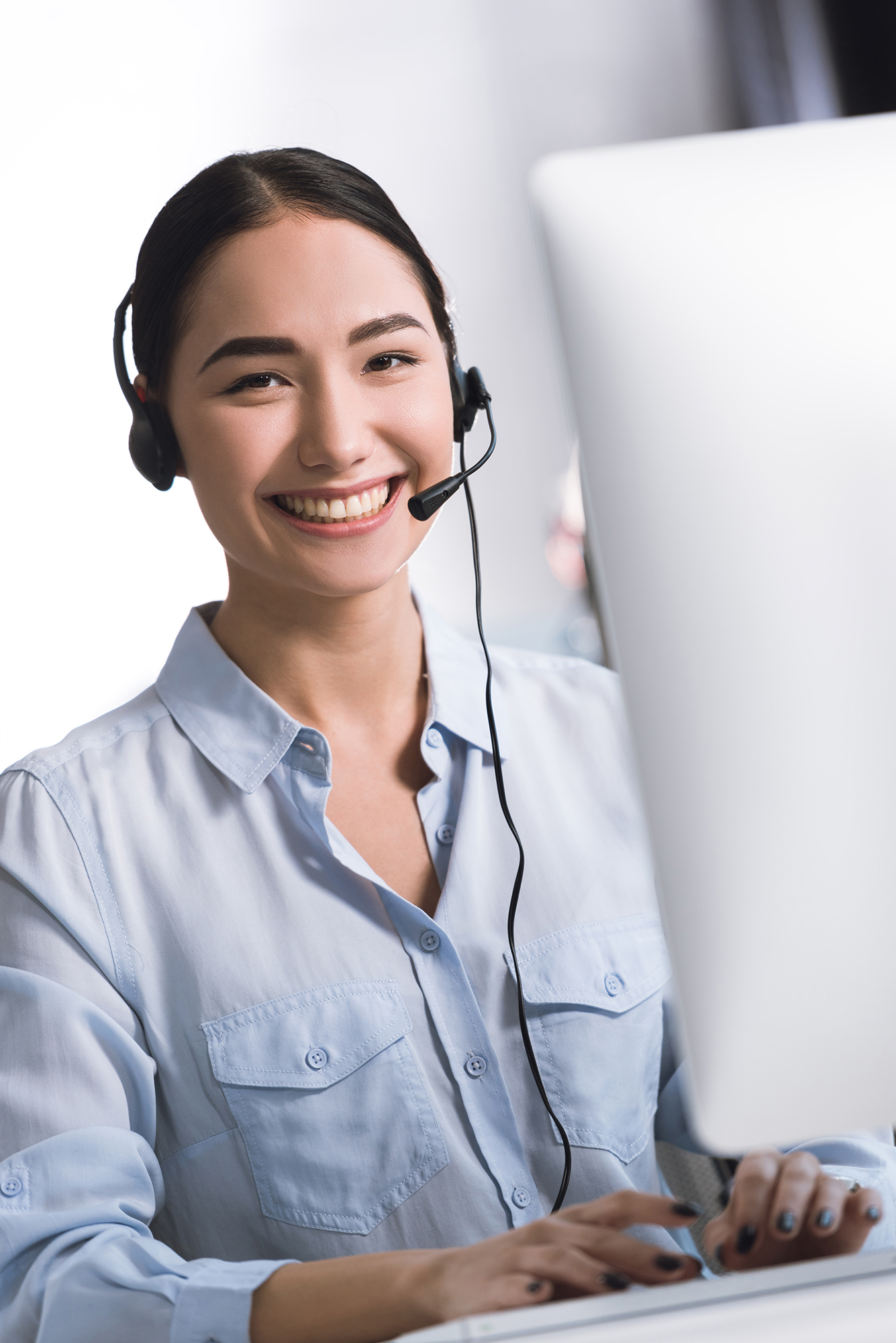portrait of smiling asian call center operator in headset lookin